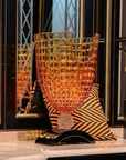 Decorative crystal vase with geometric design on a marble console styled in front of a decorative mirror.