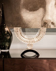 Decorative bowl with crystal details on a reflective surface, with a black vase in the foreground.