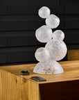 Decorative crystal sculpture with textured glass design on a wooden surface against a dark brick wall.