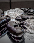 Collection of crystal sculptural objects on a reflective surface with a blurred background.