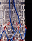 Close up of clear crystal vase with blue and red fabric cords on a black background
