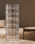 Tall clear crystal vase on a wooden surface with a blurred background
