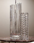 Two crystal vases on a marble surface with a neutral background