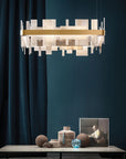 Modern chandelier hanging above a table with decorative items against a dark blue wall by Masiero available at Spacio retail stores in Mumbai & Kolkata.
