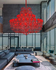 Modern living room with a large red chandelier, gray sofa, and city view.