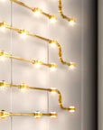 Gold finish decorative modular lights from Masiero hanging against a neutral wall