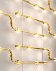 Gold finish decorative modular lights from Masiero hanging against a neutral wall