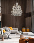 Modern living room with a chandelier, gray sofa, and orange ottoman.