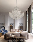 Luxurious living room with a large chandelier, gray sofa, and decorative items.