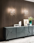 Modern gray sideboard against a wooden wall with crystal wall lights and decor accessories
