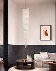 Modern living room with a crystal chandelier, sofa, and wall art.
