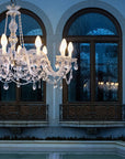 Crystal chandelier hanging above a pool with arched windows in the background