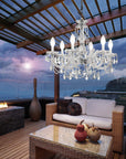 Luxurious outdoor patio with a chandelier, couch, and fire pit at night.