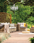 Outdoor patio with wicker furniture, outdoor chandelier floor lamp, and greenery