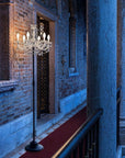 Chandelier floor lamp from Masiero in a dimly lit room with brick walls.