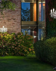 Two outdoor chandelier floor lamp in a garden setting from Masiero's Drylight Collection available at Spacio in India, with a building in the background.