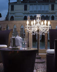 Outdoor seating area with a small floor chandelier and building in the background