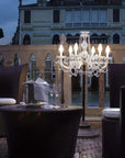 Outdoor seating area with a small floor chandelier and building in the background