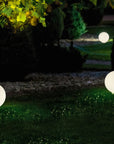 Glowing spherical garden lights in a garden setting with trees and grass.