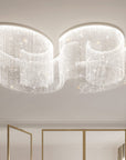 Modern chandelier hanging from a ceiling in a room with neutral walls and a window.