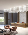 Modern hotel lobby with reception desk, chairs, and large chandelier.
