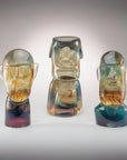 Three colorful Murano glass sculptures of stylized faces on a gray background