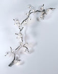 Decorative wall light fixture shaped like a branch with lights on a white background