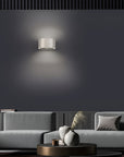 Modern living room with a gray sofa, decorative vases, and a wall-mounted rechargeable light fixture.