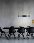 Modern black dining table with chairs under a pendant light in a minimalistic setting.