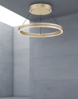 Gold circular pendant light hanging in a room with gray walls.