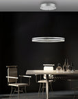 Modern dining room with a kinetic pendant light fixture against a black wall.