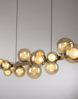 Modern kinetic chandelier with gold finish and glass shades on a neutral background