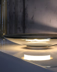 Glass table lamp on a reflective surface with a dark background