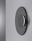 Round metallic wall light fixture on a gray background
