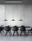 Modern black dining table with chairs and kinetic pendant lights in a minimalistic setting.