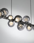 Modern kinetic chandelier with glass globe lights on a neutral background