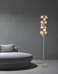 Modern floor lamp with multiple bulbs next to a gray sofa against a gray wall.