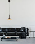 Modern living room with a black leather sofa, side table, and pendant light.