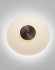 Round wall light fixture with a metallic top and glass cover on a gray background