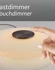 Hand touching a touch dimmer switch on a lamp with 'Tastdimmer Touchdimmer' text above.