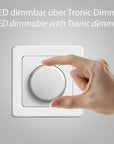 Hand adjusting a Tronic dimmer switch on a gray background