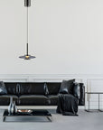 Modern living room with a black leather sofa, coffee table, and a manual lift pendant light.