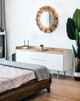 Modern bedroom with wooden bed, white dresser, and decorative mirror.