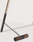 Close up of walnut wood and black floor lamp on a light gray background