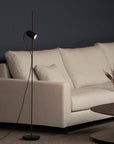 Modern living room with a light gray sofa, floor lamp, and small round table.