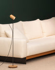 Beige sofa with a modern floor lamp against a dark wall