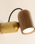 Wall-mounted lamp with wooden and brass finish on a beige background from Nomon available at Spacio retail stores in India.