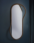 Modern oval mirror with wooden frame on a dark wall