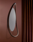 Round mirror with a wooden frame on a red wall