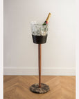 Decorative vase with a bottle on a stand against a white wall